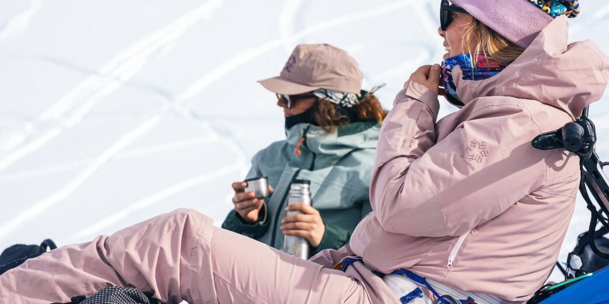 women in ski pants sitting on the snow